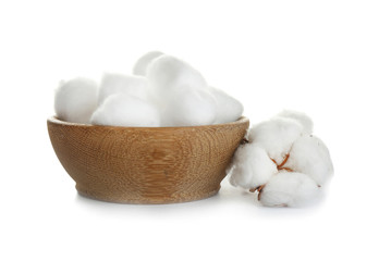 Balls of fluffy cotton in wooden bowl and flower on white background