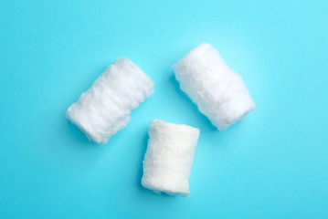 Fototapeta na wymiar Three fluffy cotton rolls on color background, flat lay