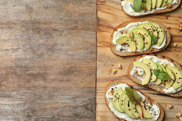 Board with avocado bruschettas on wooden table, flat lay. Space for text