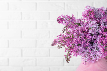Blossoming lilac flowers in vase on light background, closeup. Space for text