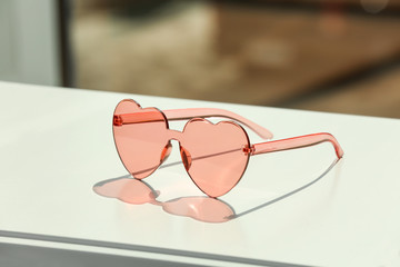 Stylish heart shaped sunglasses on table against blurred background. Space for text