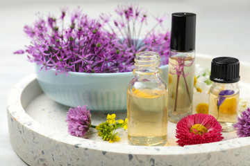 Composition with bottles of essential oils and different flowers on table, closeup