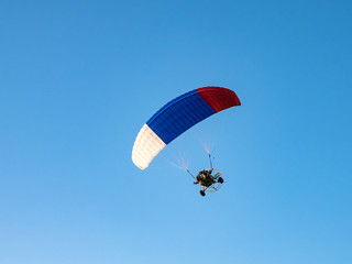 Powered parachute against the blue sky. 