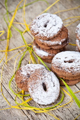 Fresh baked chocolate chip cookies with sugar powder stacks on wooden table.