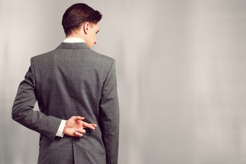 Businessman with his fingers crossed behind his back - concept for good luck or dishones