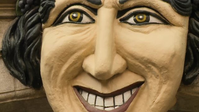 An extreme close up of the nose and mouth of a sculpted head on the top of a building 