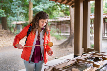 Tokyo, Japan Meiji shrine entrance water purification fountain with tourist foreign woman girl...