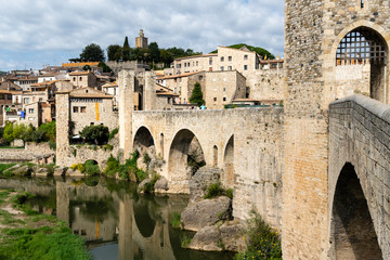 Fototapeta na wymiar Romanesque bridge across the river Fluvia with arches and defence towers in Besalu, Spain
