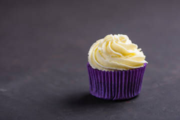 Cupcake in purple wrap on dark stone table top. Minimal concept. Copy space.