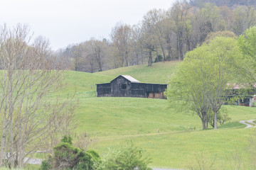Obraz premium Rural Tennessee scenery with farm countryside in spring and grass lawn with storage silo shed for hay bales on mountain