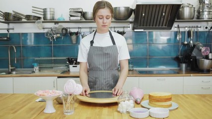 Tracking left shot of female pastry chef bringing freshly baked sponge cakes and thinking of future dessert at table in restaurant kitchen
