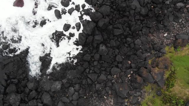 Aerial Drone Azores Portugal fly over from green grass and steps to black rocks and white waves and deep blue turquoise