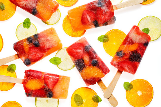 Fruit Popsicles, Homemade Fruit Ice Lolly Of Various Fruits; Mandarins, Limes, Blackberries, Blueberries, Raspberries And Strawberries With The Addition Of Lemonade On White Background, Top View. 