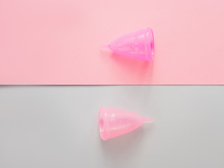 Close up of menstrual cup and ribbons over pink background. Eco-friendly concept for women's health. Innovation product in gynecology that replaced traditional approaches.