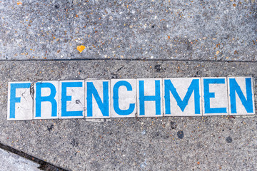 Historic old town Frenchmen street sign on sidewalk pavement in New Orleans, Louisiana famous town city during day flat top view down