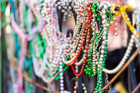 New Orleans, USA Closeup Of Multicolored Mardi Gras Beads Hanging On Fence By Colorful Building House And Nobody On Sidewalk