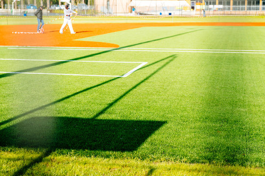 Silhouettes of people on the green sport terrain used for playing baseball