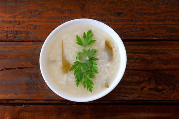 congee in ceramic bowl on rustic wooden table, traditional rice porridge typical of Asian cuisine