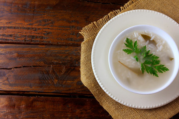 congee in ceramic bowl on rustic wooden table, traditional rice porridge typical of Asian cuisine