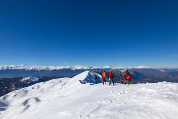 3 mountain climbers walk on snow in the mountains