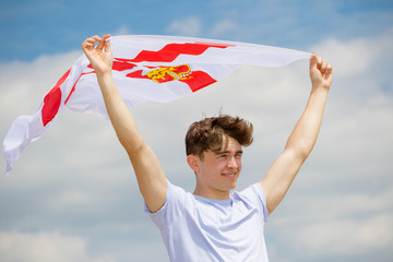 Caucasian male on a beach holding an Ulster flag