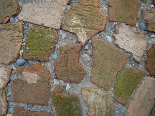 Background old road of red broken brick. The cracks are filled with gravel, sand. Textured surface.