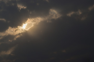 Fototapeta na wymiar Dark bright sun in sky with clouds