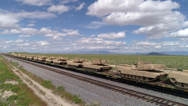 Military tanks lined up on train in the Utah desert.