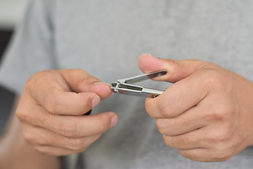 Man cutting nails using nail clipper, close-up