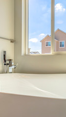 Vertical frame Glossy bathtub and wall mounted towel rod inside a bathroom lit by sunlight