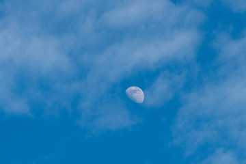 moon rise under blue sky covered with think layer of cloud