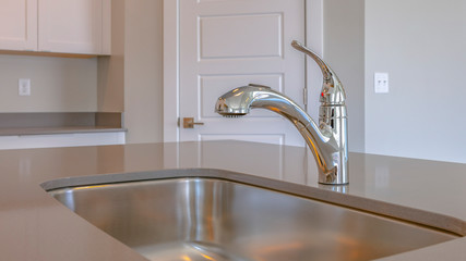 Panorama Shiny stainless steel sink and faucet on the countertop inside a kitchen
