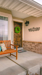 Vertical Wooden porch bench with pillows against the shiny front window