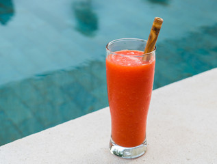 Fresh orange papaya juice in glass with bamboo tube on a  stone background near waterpool. Tropical Fruit. Top view. Free text space. © Anna