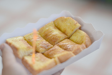 Toast topped with sweetened condensed milk in a paper dish on a wooden table.copy space