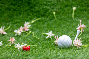Golf ball with flowers are on green grass