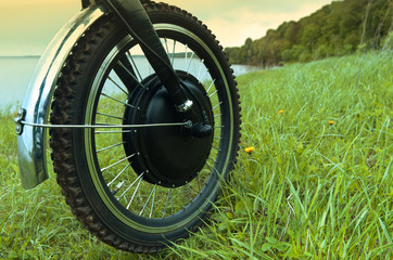 Bicicle electric . Journey into the landscape of wild nature. Motor-wheel bike on the background of green grass and landscape.