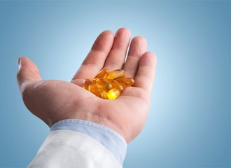 Girl eating lots of yellow pills on pastel background