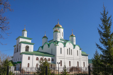 Fototapeta na wymiar White, orthodox temple with golden domes against the blue sky.