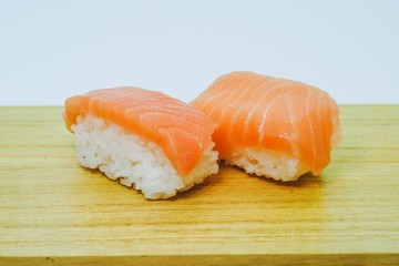 Raw Salmon Nigiri Sushi served on a wooden board against white background, a traditional japanese delicacies