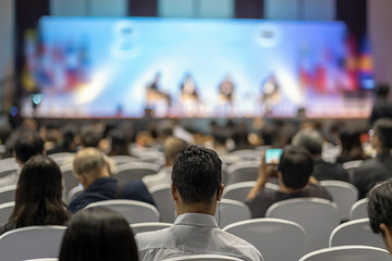 Rear view of Audience listening Speakers on the stage in the conference hall or seminar meeting,...