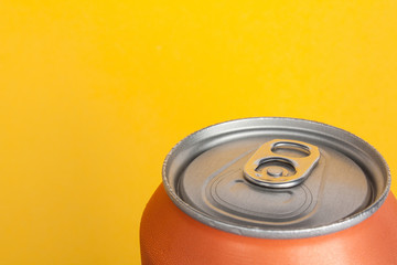 Orange closed aluminum can of soda or beer on yellow background with a place under the text