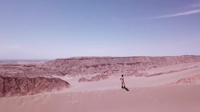 Man walking with sandboard over great Sand Dunes of the Dead Valley, Atacama desert. Slow motion