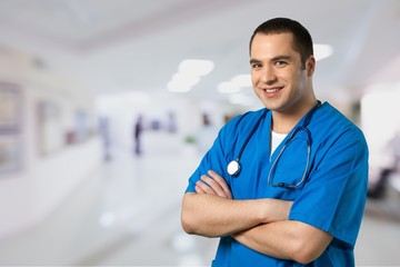 Attractive young female doctor with blurred hospital interior on background