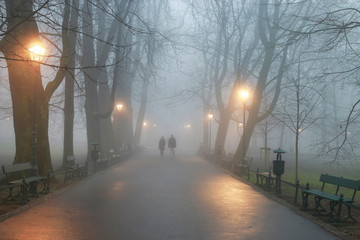 Couple walking in mist. October morning in Planty Park