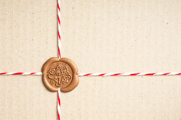 Close up of rope that tied to paper box, it's sealing with sealing wax stamp has the word pattern Thank you