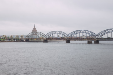 Obraz premium City Riga, Latvian Republic. Railway bridge with river Daugava and buildings. Urban view. May 27. 2019 Travel photo.