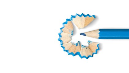 Some colored pencils of different colors and a pencil sharpener and pencil shavings on a white...