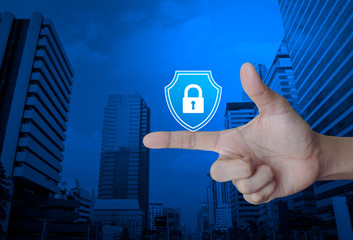 Hand pressing padlock with shield flat icon over modern office city tower and skyscraper, Business security insurance concept