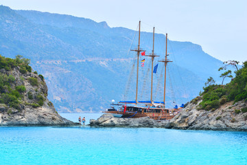 Obraz premium Wooden vintage ship is in the bay between mountain rocks